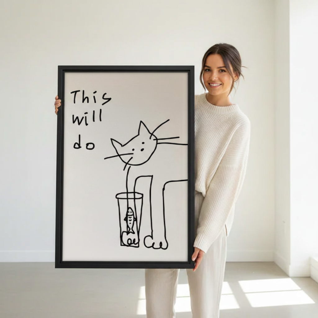 Woman holding large framed this will do funny cat fish glass minimalist line art print in black frame showing actual print size in bright white studio