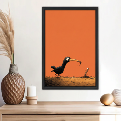 Funny black bird catching worm orange background minimalist wall art print in black frame above wooden sideboard with pampas grass vase and white candle in boho entryway