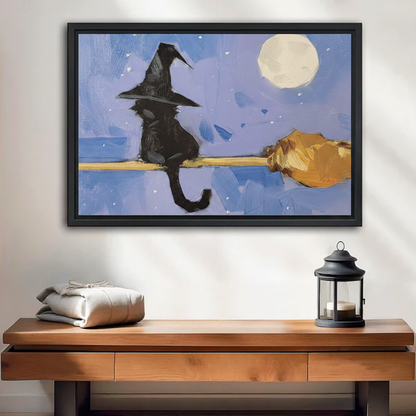 Black cat witch hat riding broomstick framed wall art print, black frame, blue moonlit night oil painting style, displayed above a wooden console table in a warm neutral entryway with lantern decor