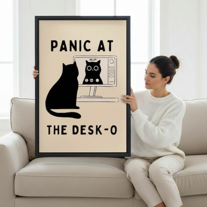 Woman holding large framed funny black cat panic at the desk-o computer humor wall art print in black frame showing actual print size on cream sofa in bright minimalist living room