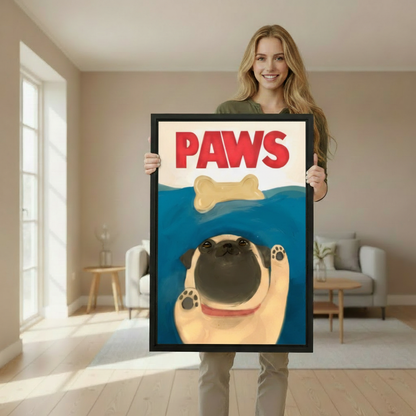 Woman holding large framed funny pug PAWS Jaws parody swimming bone wall art print in black frame showing actual print size in bright minimalist living room with cream sofa and wooden side table