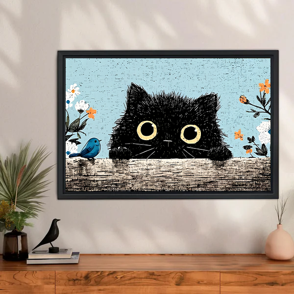 Fluffy black cat peeking over wall with yellow eyes blue bird and orange wildflowers vintage illustration framed wall art hung above wooden sideboard with plant and ceramic bird decor

