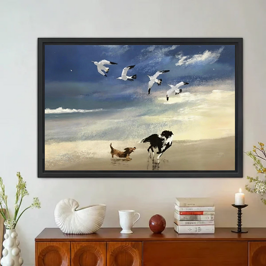 Black framed wall art of two dogs and seagulls on beach above sideboard
