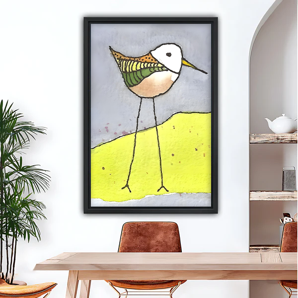 Quirky illustrated sandpiper bird on yellow dune framed canvas wall art in black frame, whimsical colorful bird print for dining room decor