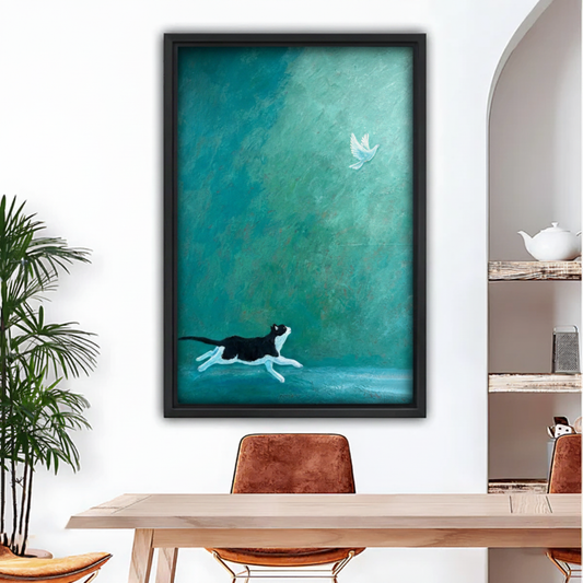 Black and white cat chasing white bird framed wall art print, black frame, teal oil painting style, displayed above a wooden dining table in a modern boho dining room with indoor palm