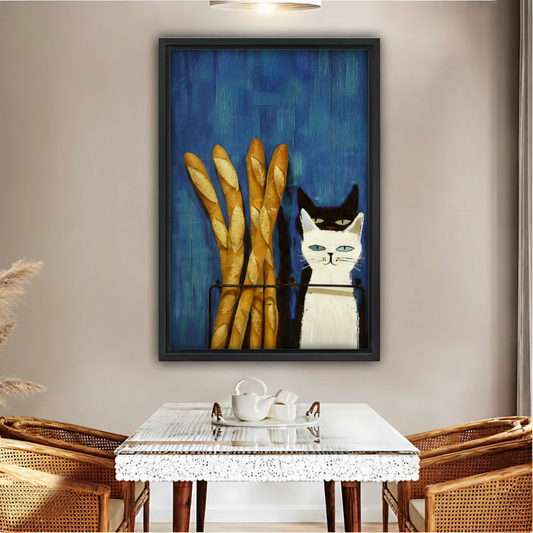 Black and white cat with French baguettes framed wall art print, black frame, bold blue oil painting style, displayed above a rattan dining table in a warm boho dining room with wicker chairs