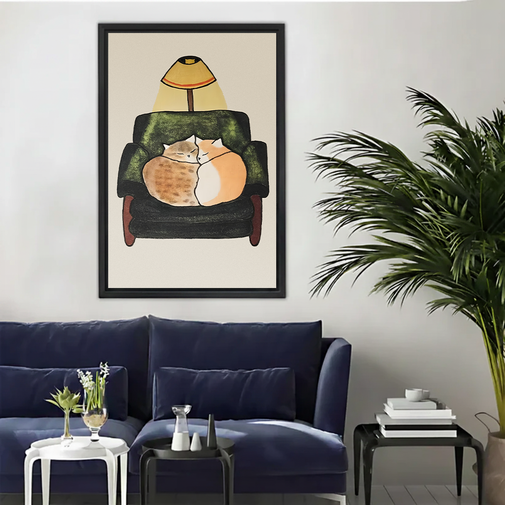 Cozy two cats cuddling armchair illustration framed wall art print displayed above dark blue velvet sofa in living room