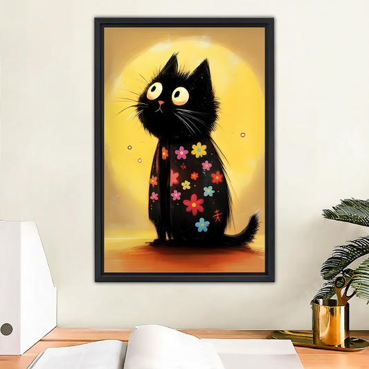 Floral black cat with colorful flowers and yellow moon whimsical cartoon framed wall art hung on white wall above wooden desk with open notebook and gold pen holder in modern home office