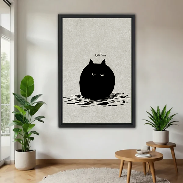 Grumpy round black cat minimalist funny framed canvas wall art in black frame displayed in bright living room with tropical plants and wooden side table