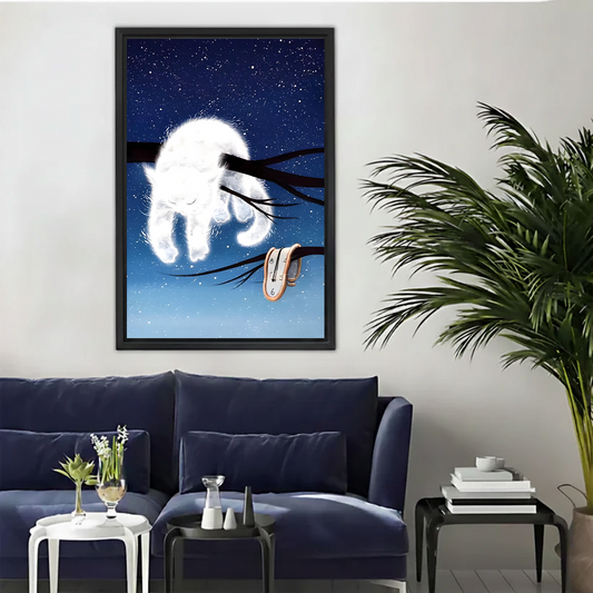 White cat starry night surreal framed canvas wall art with melting clock hung on white wall above navy blue sofa with palm plant in modern living room