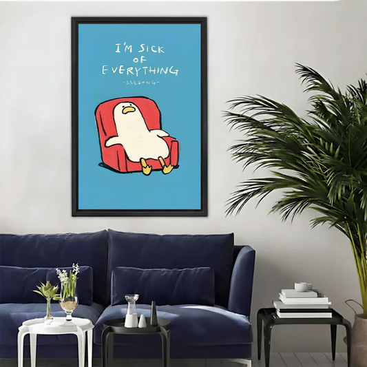 White cartoon duck slouched in red armchair with I'm sick of everything handwritten text on blue background funny minimalist illustration framed wall art hung on white wall above navy blue sofa with white side table glass vase stacked books and large palm plant in modern living room