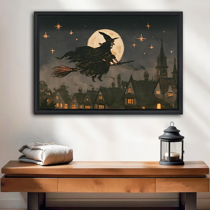 Woman holding black-framed moonlit witch canvas wall art showing a flying witch above a village beneath a golden moon.