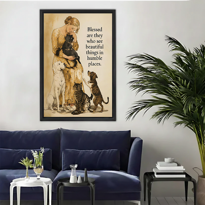 Woman in yellow floral dress holding black cat surrounded by white labrador tabby cat and dachshund vintage watercolor illustration with blessed beautiful things humble places quote framed wall art hung on white wall above navy blue sofa with white side table glass vase and large palm plant in modern living room