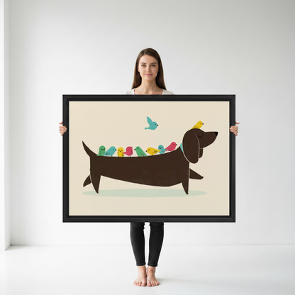 Woman holding large framed funny dachshund colorful birds illustration wall art print in black frame showing actual print size in bright white studio