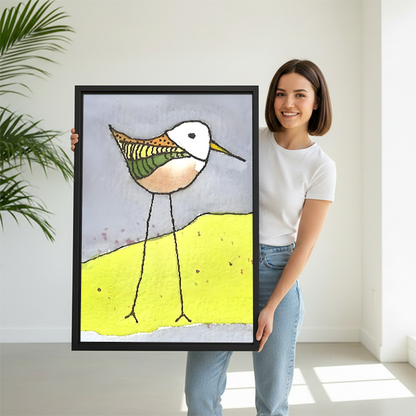 Woman holding quirky illustrated sandpiper yellow dune framed canvas wall art, large size colorful bird print for home decor