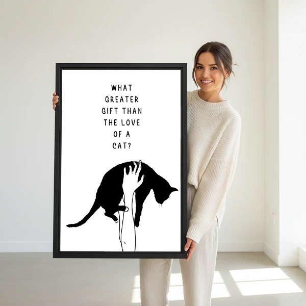 Smiling woman in cream sweater holding large what greater gift than the love of a cat minimalist black and white framed canvas print in bright white studio with natural light