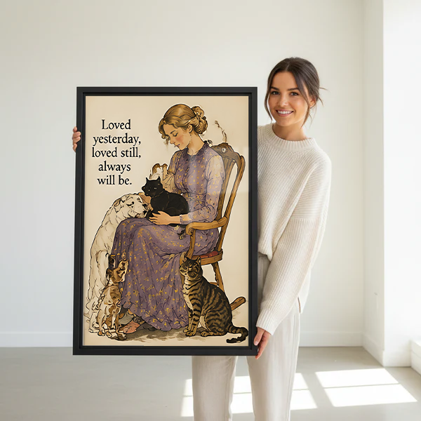 Smiling brunette woman in white sweater holding large loved yesterday always will be woman pets vintage watercolor framed canvas print with black cat white dog beagle and tabby cat in bright white room with natural light