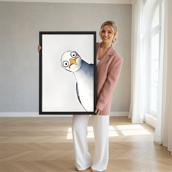 Woman in pink blazer holding large tilted seagull watercolor framed canvas print with round eyes and yellow beak in bright open studio