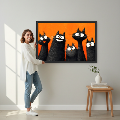Smiling brunette woman in white shirt and jeans holding large five funny black cats orange background pop art framed canvas print beside wooden stool with white vase and stacked books in bright sunlit hallway