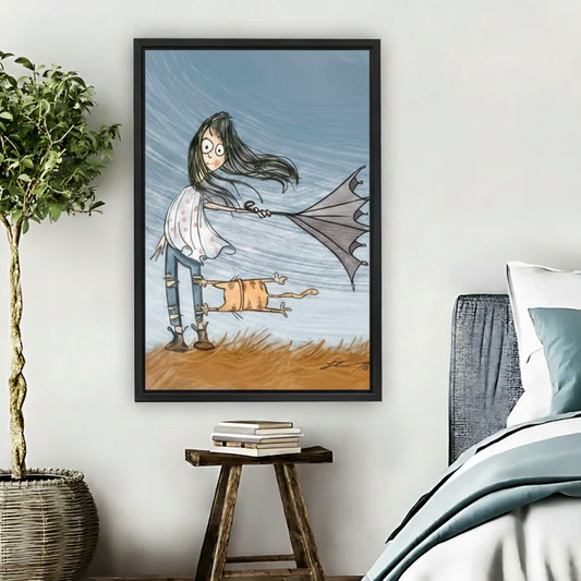 Whimsical windy girl and cat framed wall art in bedroom next to bed with blue pillows