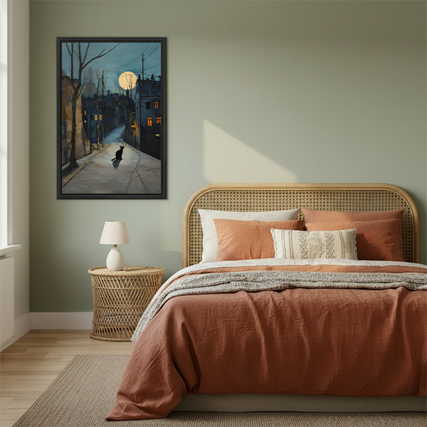 Framed black cat on moonlit street watercolor print above a boho bedroom bed with terracotta bedding, atmospheric night wall art