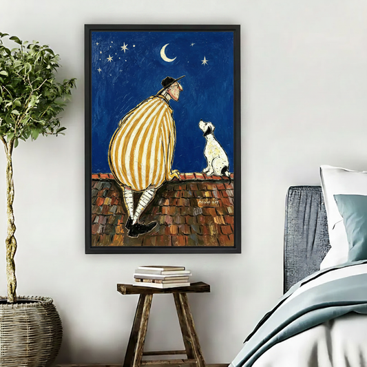 Man and dog sitting on rooftop watching moon stars night sky oil painting wall art print in black frame above wooden stool with books and wicker basket in boho bedroom