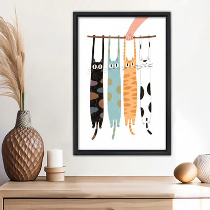 Four cats hanging from stick funny illustration wall art print in black frame above wooden sideboard with pineapple vase and white candle in boho living room