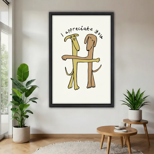 "I Appreciate You" funny dogs hugging framed wall art print, black frame, whimsical cartoon illustration on cream background, hung on white wall in a bright minimalist living room with fiddle leaf fig and round side table