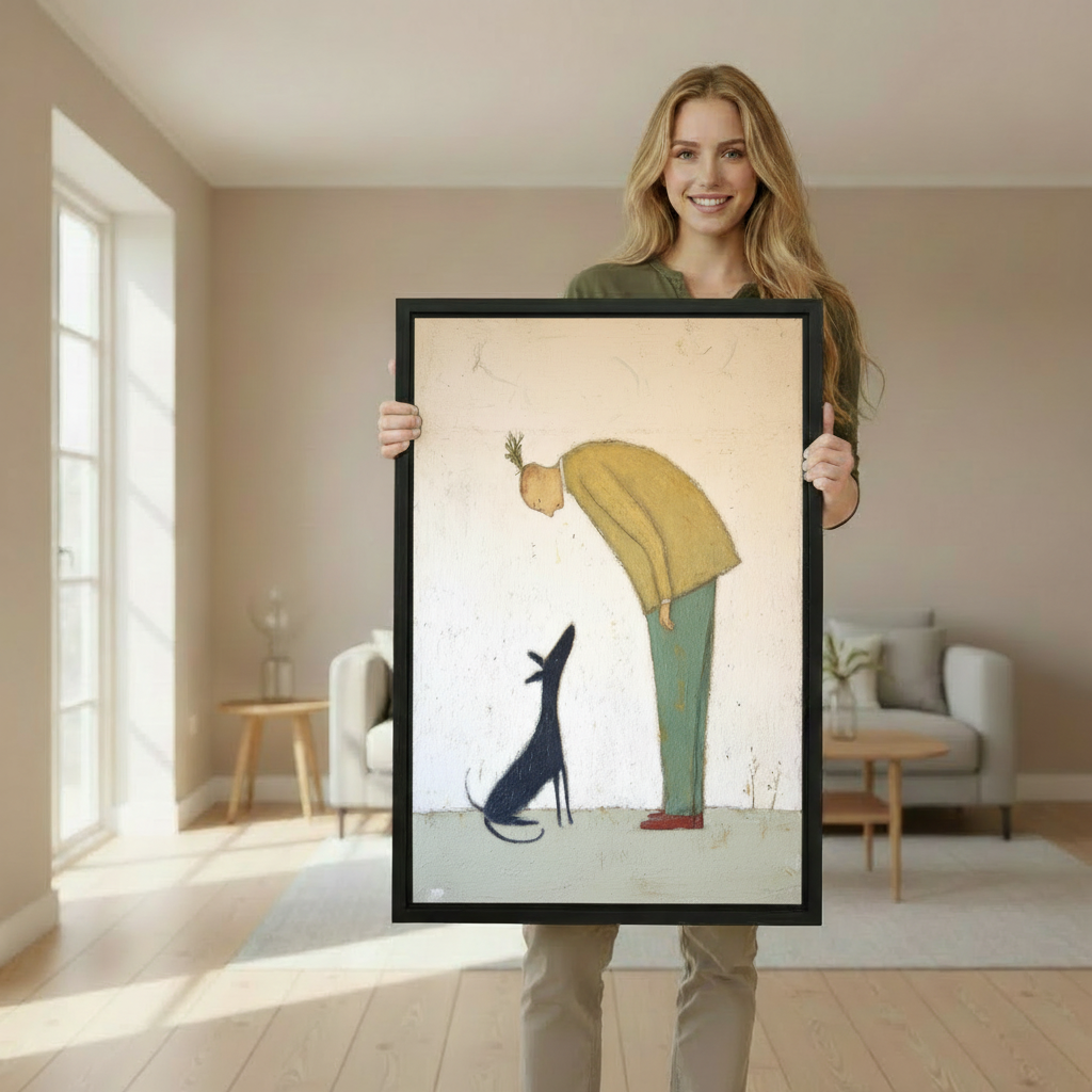 Woman holding large framed man in yellow sweater and black dog whimsical minimalist wall art print in black frame showing actual print size in bright Scandinavian living room with cream armchairs