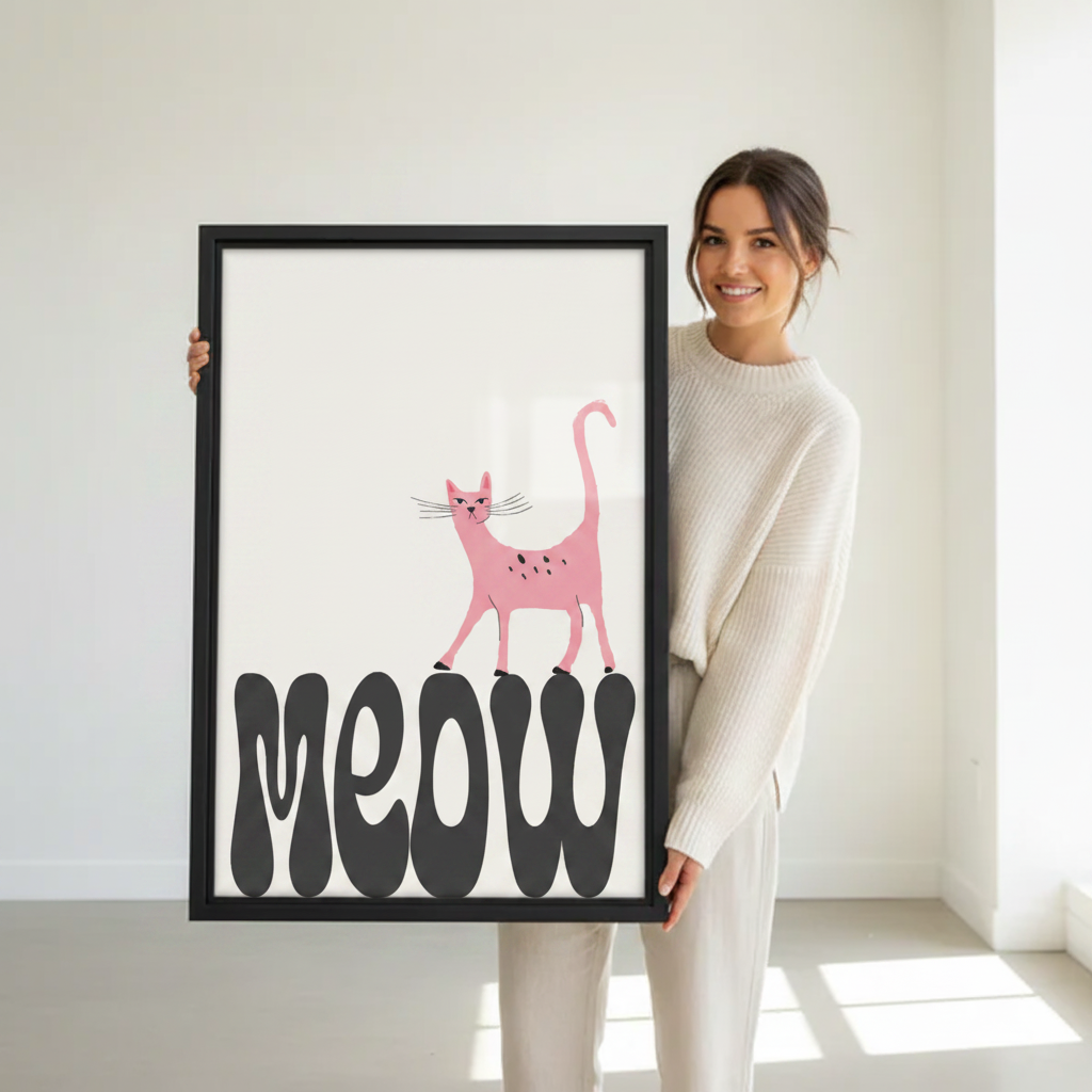 Woman holding large framed pink cat meow typography wall art print in black frame showing actual print size in bright minimalist white studio