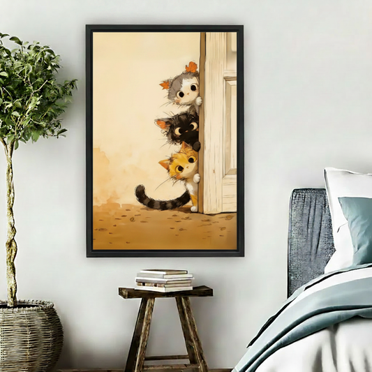 Cute peeking cats canvas wall art print in black frame hanging in cozy bedroom with blue bedding and green plant