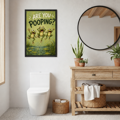 Framed are you pooping frogs canvas wall art hanging beside a round mirror and potted plants in a bathroom.