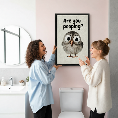 Two women hanging framed are you pooping owl canvas wall art on a bright pink bathroom wall.