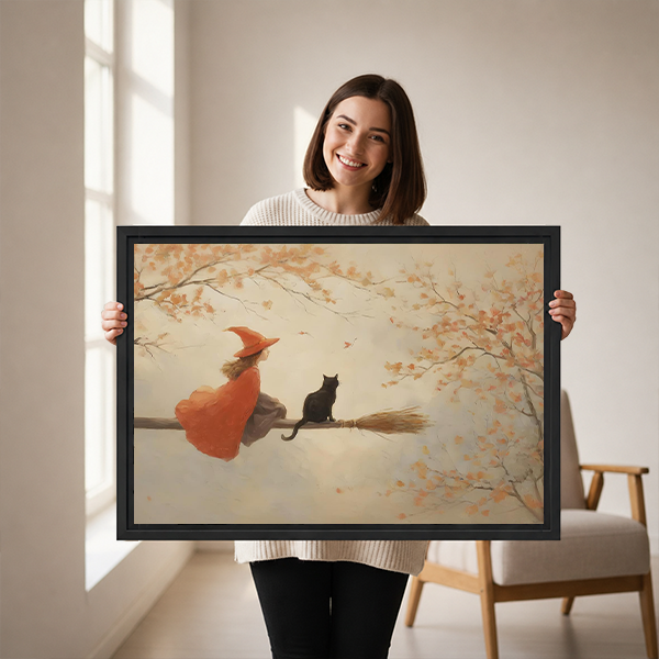 Woman holding framed autumn witch and black cat canvas wall art showing warm oil-painting style broomstick scene
