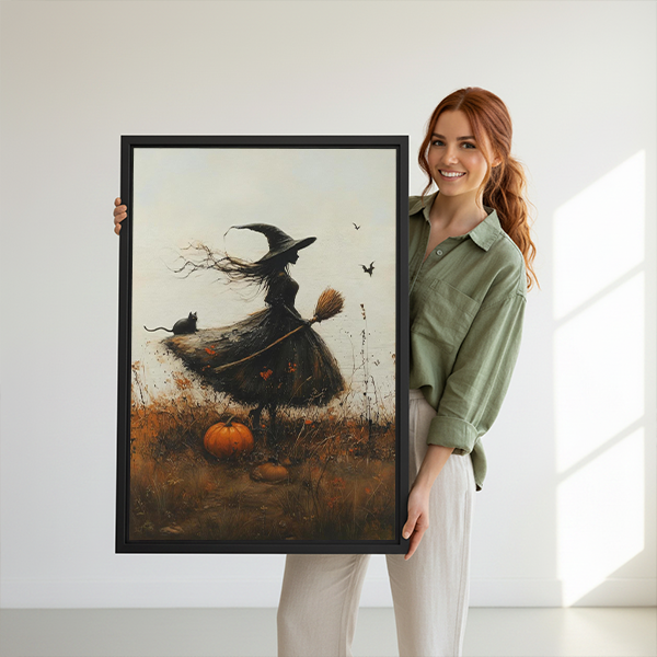 Autumn witch canvas wall art in a black frame between potted plants above small wooden tables.