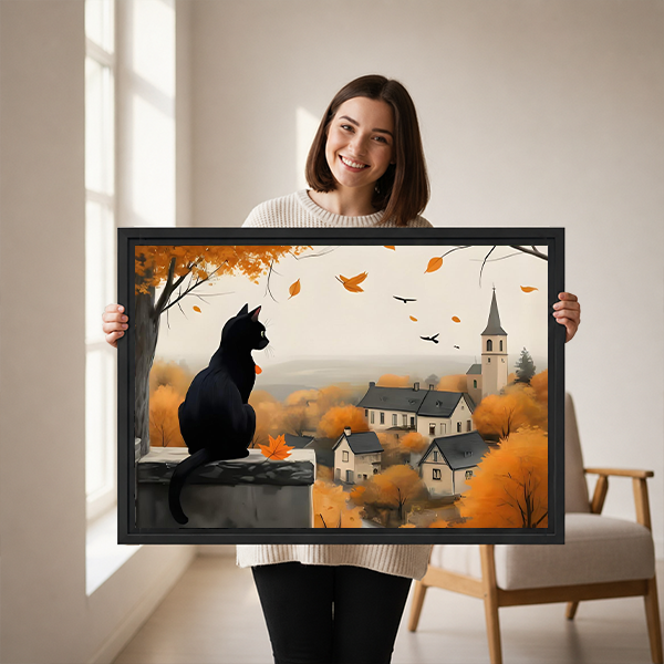Framed black cat autumn village canvas wall art hangs above a light sofa with warm countryside colors.