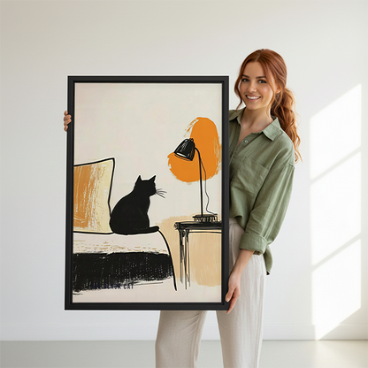 Black framed black cat and lamp canvas wall art with an orange accent, displayed beside plants and tables.