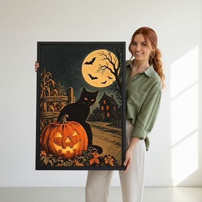 Black-framed black cat and pumpkin canvas wall art featuring a glowing jack-o’-lantern displayed between green houseplants.