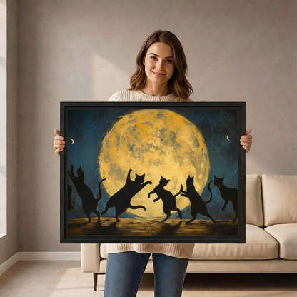 Smiling woman holding a large black-framed canvas art print of five black cat silhouettes dancing under a dramatic golden full moon with crescent moons in a deep teal night sky, painted in a bold impressionist oil style