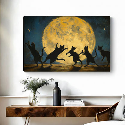 Frameless gallery-wrap canvas of five black cat silhouettes in dynamic dancing poses backlit by a dramatic golden full moon with crescent moons in a deep teal night sky, hung above a walnut console table with a black vase and stacked books