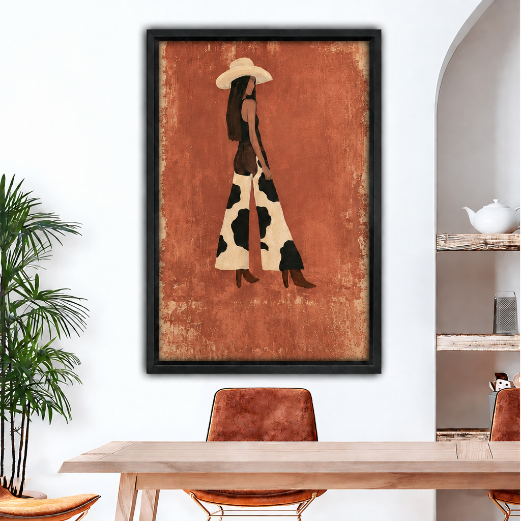 Minimalist boho western cowgirl in wide-brim hat and cow print maxi dress with brown boots on distressed terracotta background framed canvas above wood dining table with leather chairs and white arched wall⠋