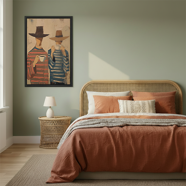 Woman holding black-framed coffee companions canvas wall art depicting two hat-wearing figures with white cups.