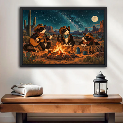 Woman holding framed cowboy cats campfire canvas wall art featuring three cats beneath a starry desert sky.