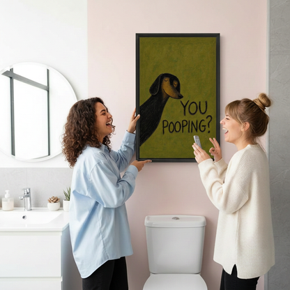 Two friends laughing beside framed dachshund You Pooping canvas wall art in a bathroom
