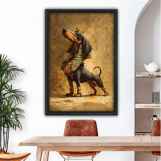 Black framed oil-style art print of a proud dachshund in golden pharaoh robes and crown, hung above a dining table with leather chairs in a bright arched interior