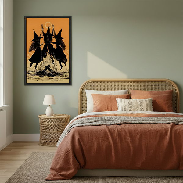 Vintage dancing witches canvas wall art in a black frame beside a rattan bed with warm terracotta bedding.