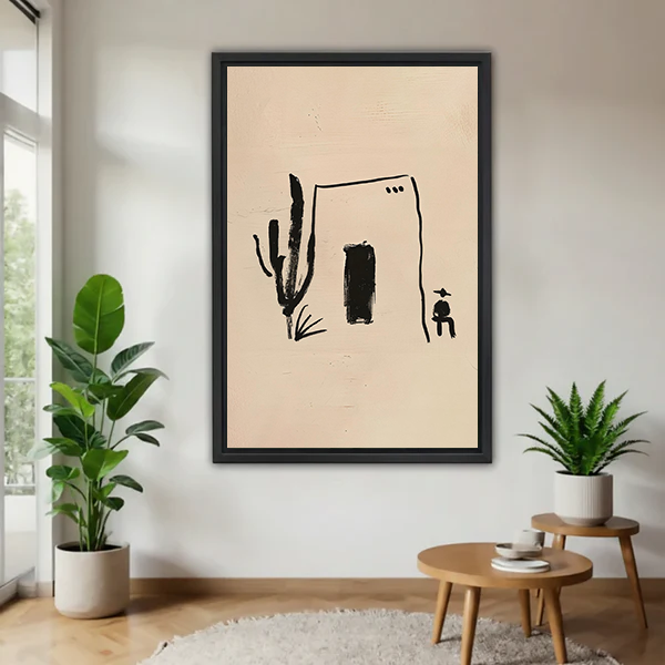Black-framed desert house and cactus canvas wall art with minimalist black marks displayed above a cream living room sofa.