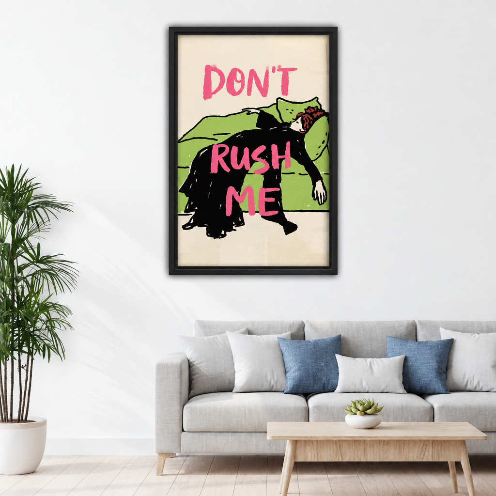 Framed canvas of retro illustration of a woman in black dress leaning over a green sofa with bold pink "Don't Rush Me" quote on cream background above grey sofa with blue pillows