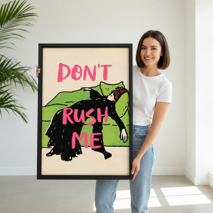 Woman holding large vertical framed canvas of vintage-style illustration of a woman in black dress draped over a green sofa with bold pink "Don't Rush Me" text on cream background