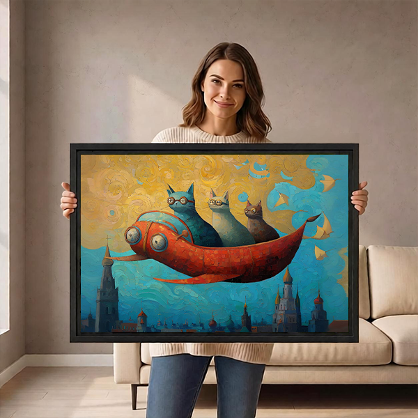 Woman holding a large framed fantasy flying cats wall art print showing three cats on a red fish over a magical city, demonstrating print scale and black frame
